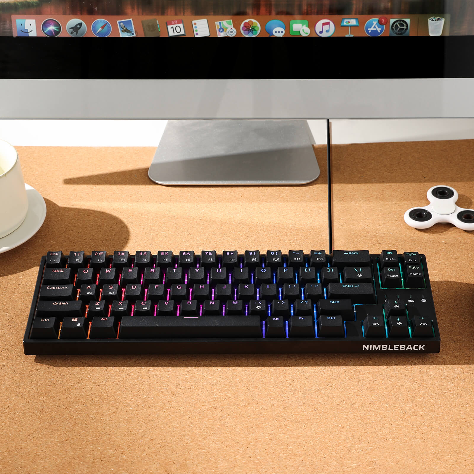 Black keyboard with RGB lighting on a desk in front of a computer monitor.