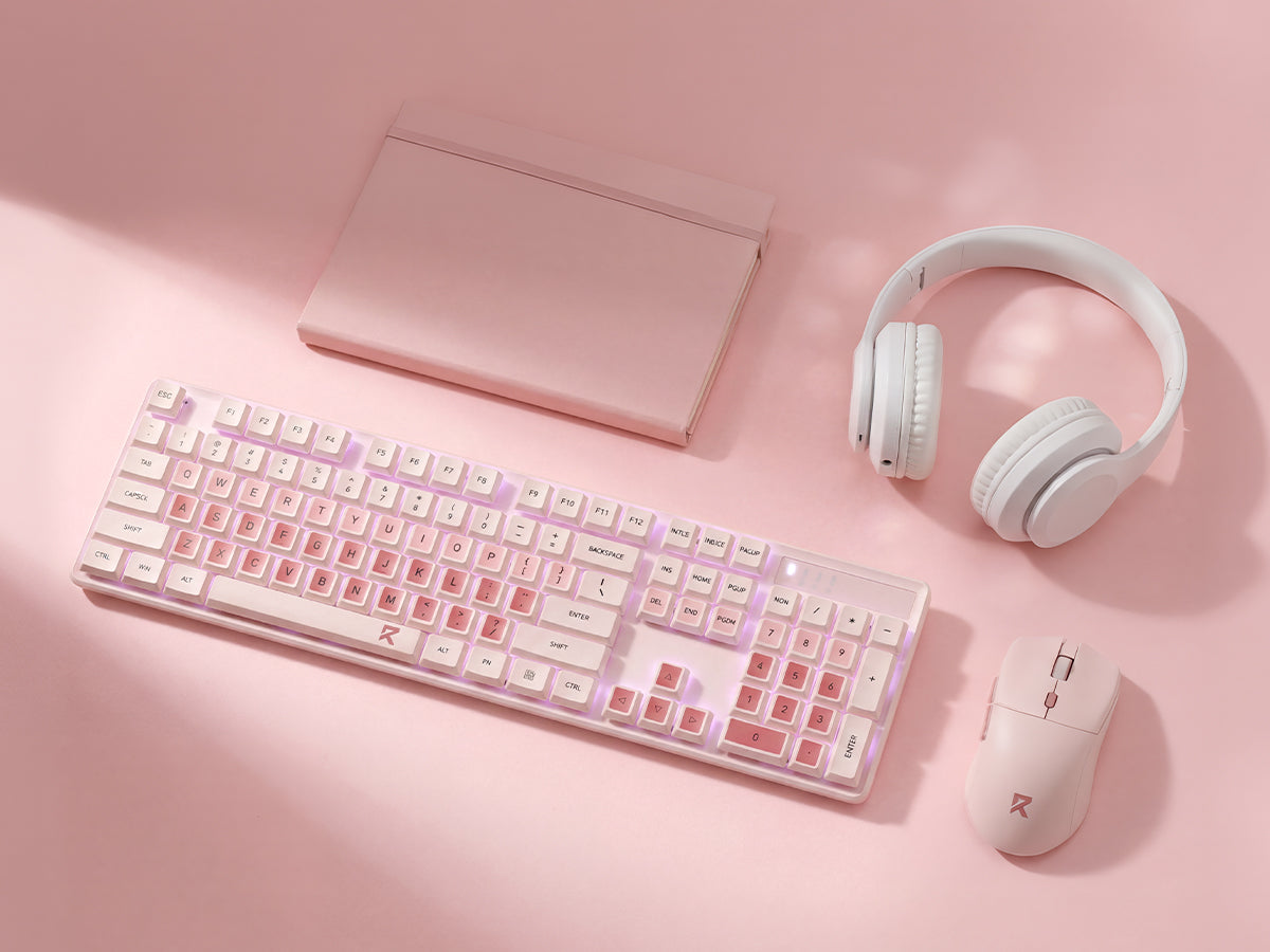 A pink and white tech setup set including a wireless keyboard, mouse, over-ear headphones, and a slim notebook, arranged on a soft pink background with artistic shadows.