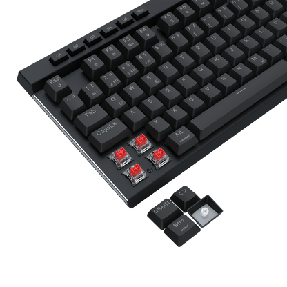 A close-up of a black mechanical keyboard with silver trim and four exposed red switch capsules near the bottom left, plus a small detached keycap cluster on a black background.