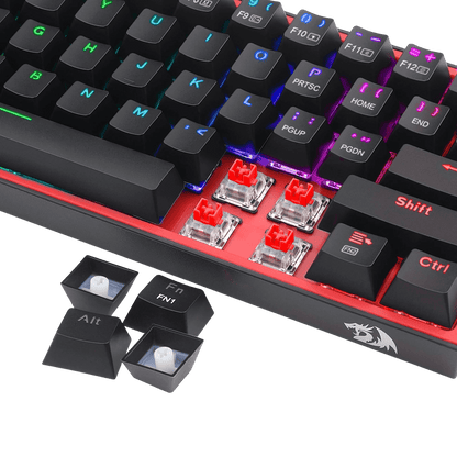 A close-up of a mechanical keyboard with black keycaps, red switch housings, and RGB backlighting, shown on a black background with two removable keycaps placed in front.
