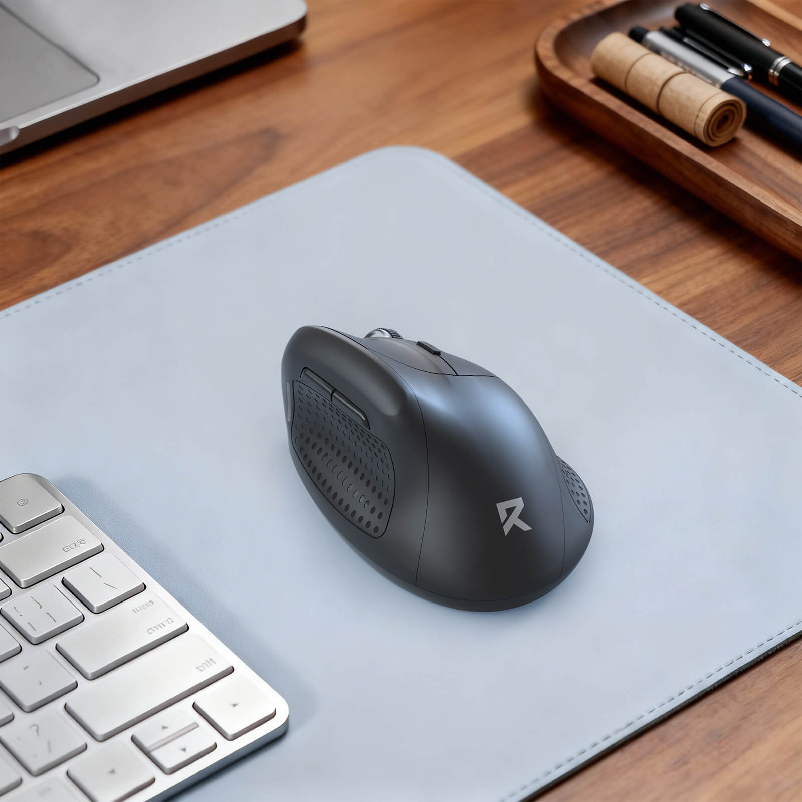Black mouse on a gray mouse pad with a keyboard and office supplies in the background.