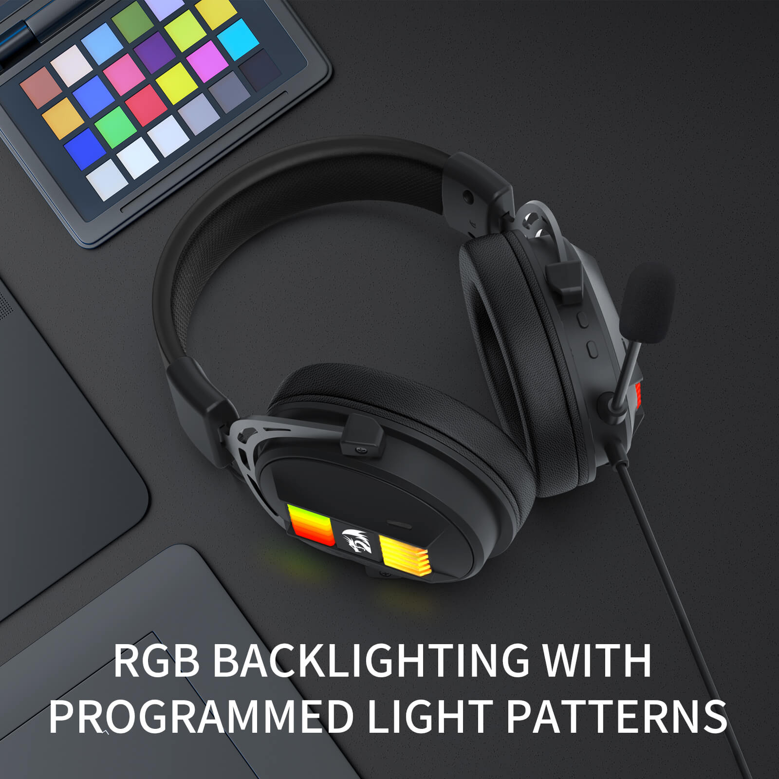 Redragon Black gaming headset with RGB backlighting on a dark surface next to a laptop.