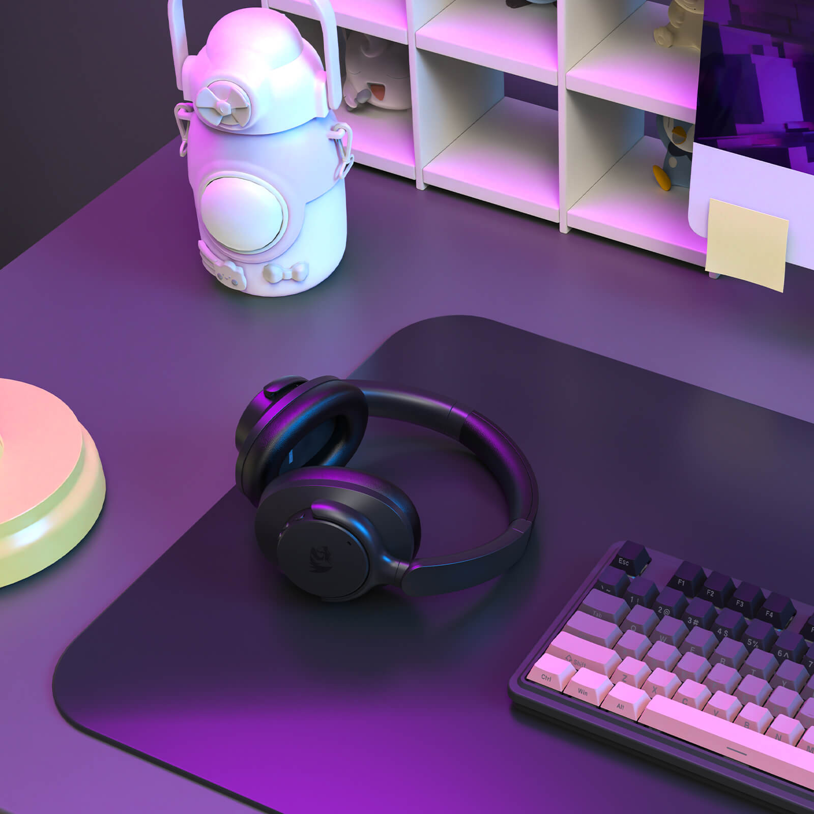 Black headphones on a purple mouse pad with a keyboard, in front of a shelf with decorative items.
