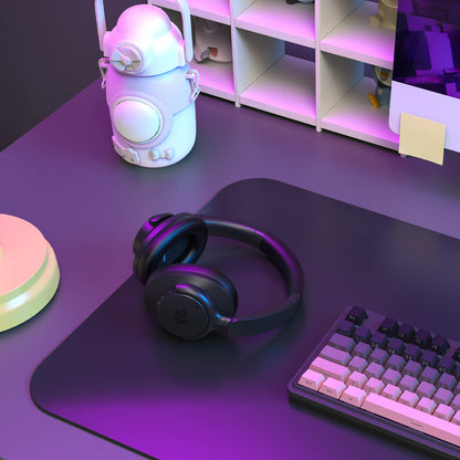 Black headphones on a purple mouse pad with a keyboard, in front of a shelf with decorative items.