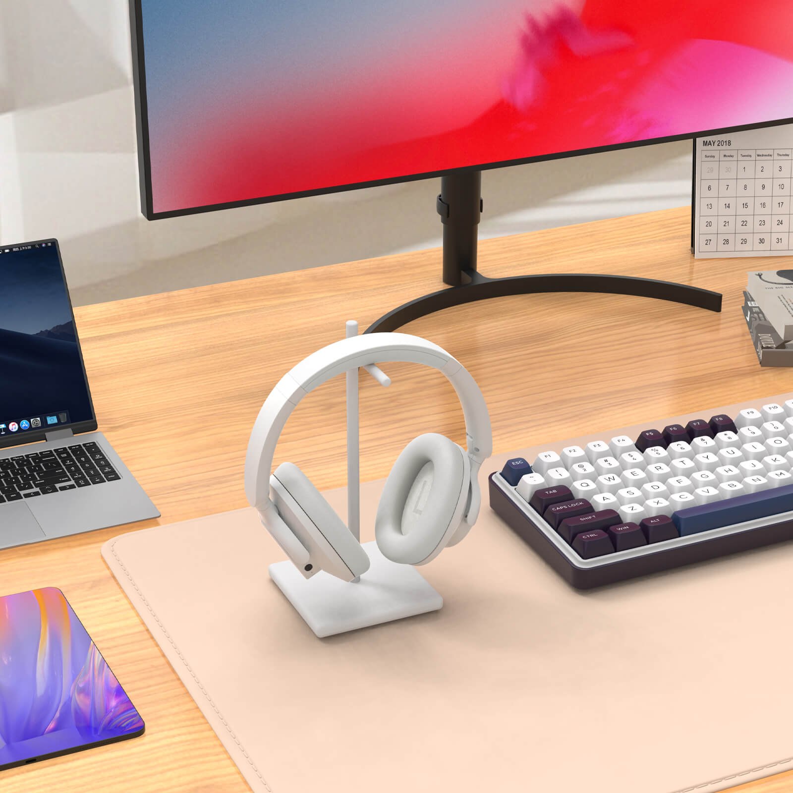 Desk setup with a monitor, laptop, keyboard, and headphones on a desk.