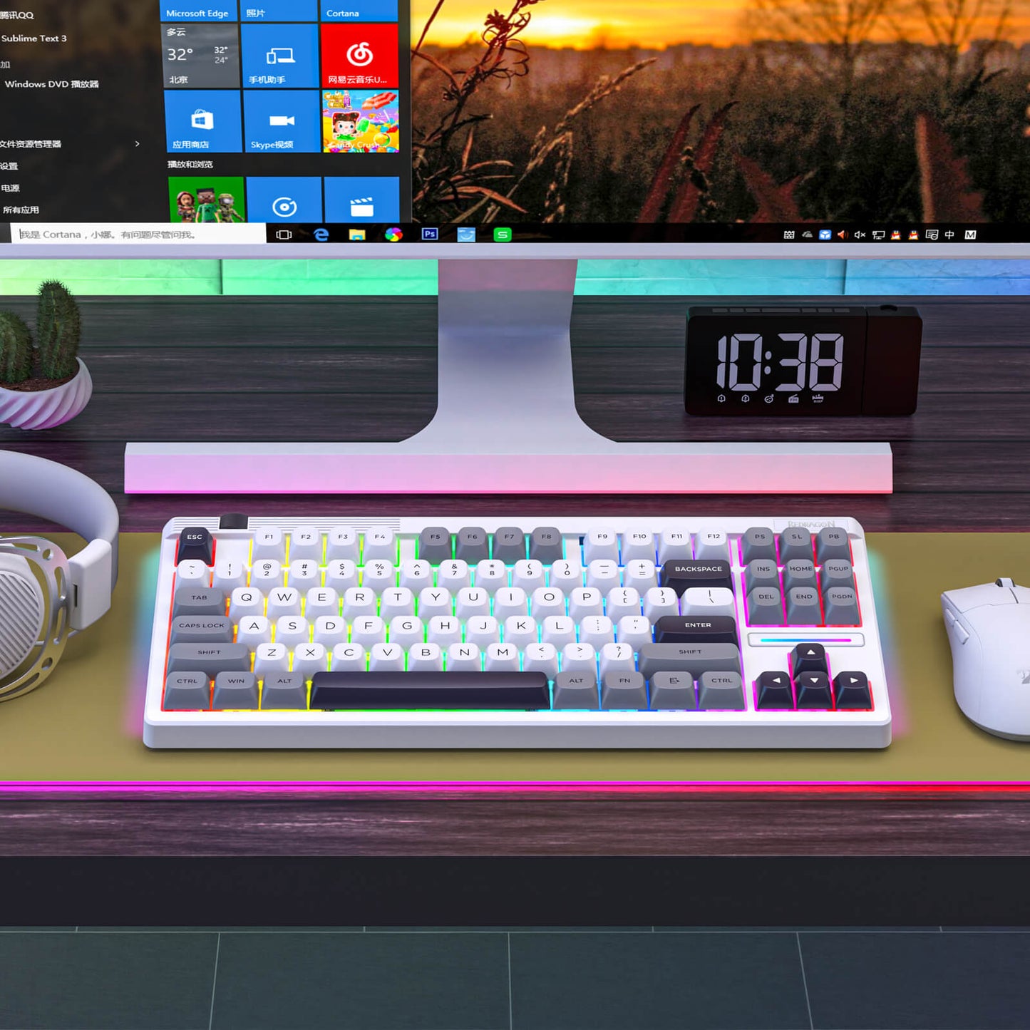Redragon K729 PRO Keyboard on a desk with a computer monitor, clock, and headphones in the background.