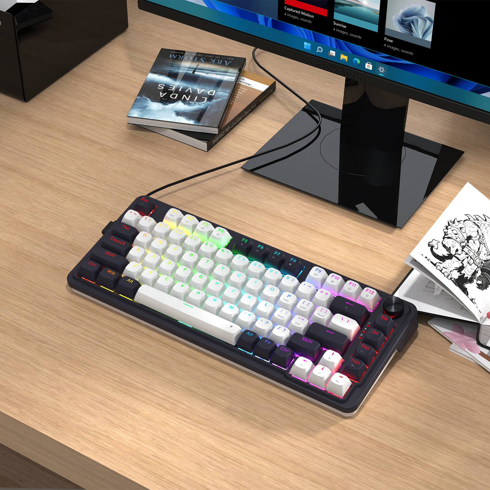 Gaming keyboard with RGB lighting on a desk next to a computer monitor and books.