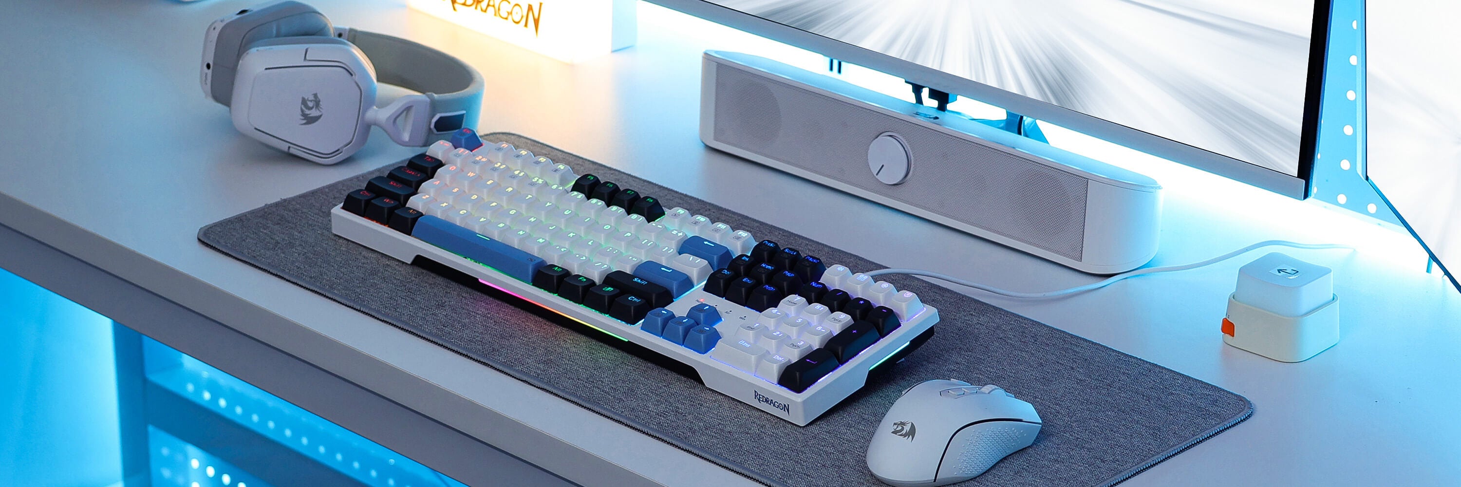 Redragon Keyboard and mouse setup on a desk with a monitor and speakers in the background