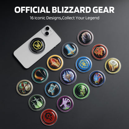 Against a dark surface, this image displays "OFFICIAL BLIZZARD GEAR" (with the tagline "16 Iconic Designs, Collect Your Legend"): a silver smartphone (with a "W"-logo grip attached) sits beside 16 circular phone grips, each featuring distinct Blizzard-themed art (like symbols, weapons, and creatures from its franchises).